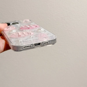 Detail of pink fish and pearl decorations on a clear glitter phone case for iPhone