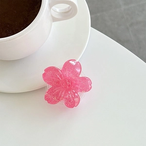 Close-up of translucent pink flower phone grip with glitter and white coffee cup on a desk