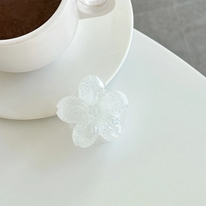 Close-up of a white flower phone grip with glitter resin finish on a white table