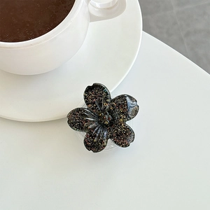 Close-up of a floral phone griptok with black glitter resin on a white desk