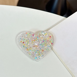 Detailed view of heart-shaped acrylic phone grip with colorful glitter and star sequins