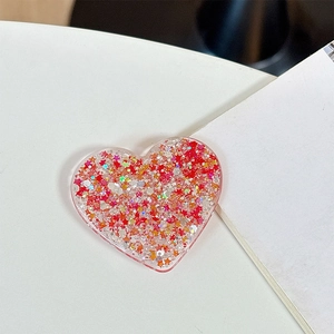 Close-up of heart-shaped glitter phone grip with red star sequins and resin finish