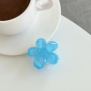 Close-up of a blue glitter cherry blossom phone socket stand on a white desk with coffee