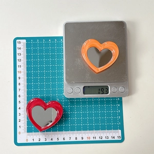 Macro detail of heart-shaped phone mirror showing 5.5cm size and 19.3g weight