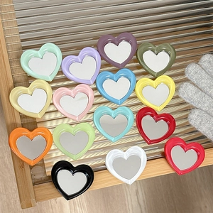 Collage of colorful heart-shaped phone grip mirrors arranged on a wooden tray