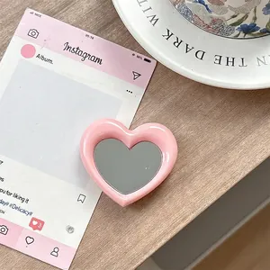 Detailopname van de roze hartvormige spiegeltelefoonhouder op een houten tafeloppervlak