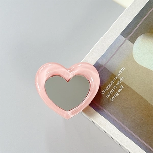 Detailed view of heart-shaped pink phone grip mirror with glossy resin frame finish