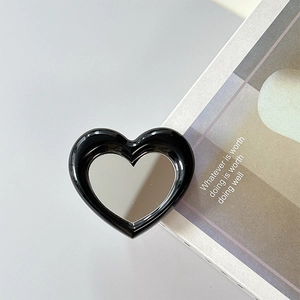 Close-up of black heart-shaped phone griptok with a built-in makeup mirror on a magazine