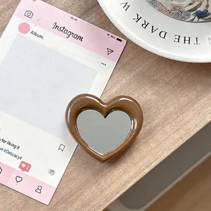 Bruine hartvormige telefoonhouder met spiegel op een houten bureau-omgeving