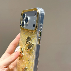 Detail view of the iPhone case showing golden glitter finish and 3D bow decorations