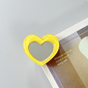 Detailed view of heart-shaped yellow marble mirror phone grip on minimalist book