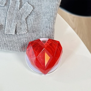 Macro shot of red 3D faceted heart phone grip holder with crystalline texture on desk