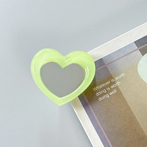 Close-up of heart-shaped phone grip with pale green frame and integrated makeup mirror