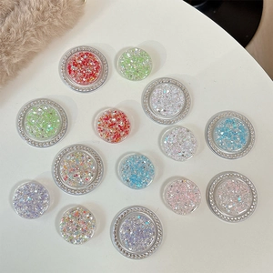 Colorful glitter and rhinestone round phone grip sockets displayed on light surface