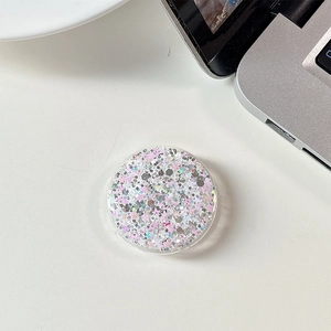Close-up of a round phone socket stand with pink and silver sequins on a white desk