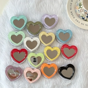 Flat lay of colorful heart-shaped phone stands with mirrors on white plush background