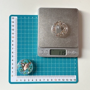Macro shot of glitter heart phone grip showing 4cm diameter on a blue cutting mat