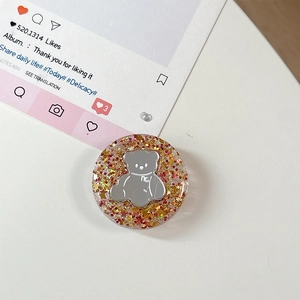 Detailweergave van ronde hars telefoonhouder met zilveren beer embleem en rode glitter