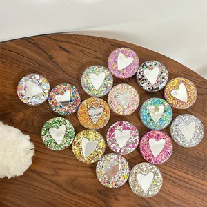 Collage of 16 colorful glitter heart phone grips on a textured dark wood background