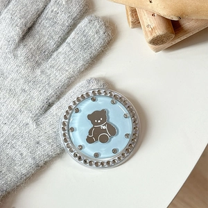 Close-up of a blue bear phone grip with rhinestones on a knitted glove background
