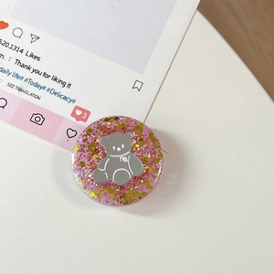 Macro-opname van ronde telefoonhouder met roze glitterbasis en een grijze beerversiering