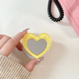Macro shot of yellow heart-shaped folding phone grip with built-in mirror detail