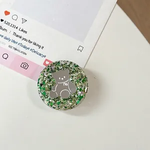 Detail van ronde telefoonhouder met 3D zilveren beer op groene glitter achtergrond