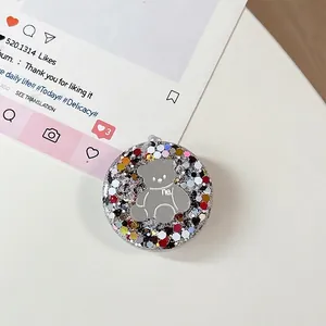 Detailopname van ronde telefoonhouder met zilveren beertje en kleurrijke glitters