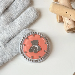 Detail of orange bear phone grip featuring sparkling rhinestones on a knitted backdrop