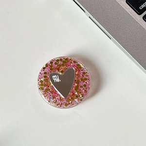 Close-up of pink glitter phone grip with heart mirror and mine. text on a white desk