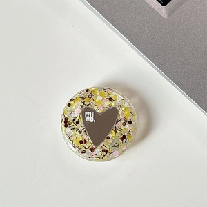 Detail of round phone griptok with heart mirror, colorful sequins, and mi ne. text