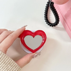 Detail of red heart-shaped magnetic phone grip with integrated mirror in Y2K style