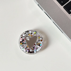 Close-up of a heart mirror phone grip with colorful glitter and 'mine:' text detail