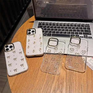 Sparkly iPhone case with 3D gold bow and rose patterns on a stylish desk setup