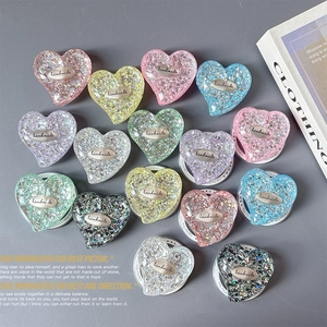 Flat lay of colorful heart-shaped sequin phone grip holders with handmade metal labels