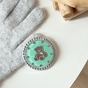 Detailed view of mint green bear phone grip with rhinestones on a knitted backdrop