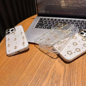Detailed close-up of four floral and bow glitter phone cases on a warm wooden desk