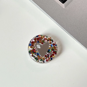 Close-up of heart mirror phone grip with colorful sequins on a desk workspace