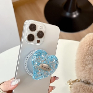 Blue sequin heart-shaped collapsible phone socket with handmade tag on white smartphone
