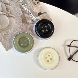 Three candy colored button style expanding phone grips in olive, black and cream finishes