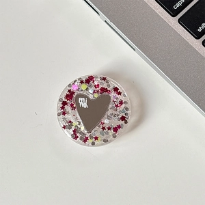 Detail of glitter resin phone grip with heart mirror and silver laptop background