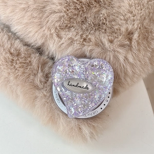 Detail of heart-shaped glitter phone grip with handmade plaque on plush fabric