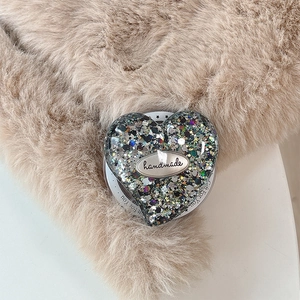 Close-up of heart-shaped phone grip with glitter sequins and handmade metal tag