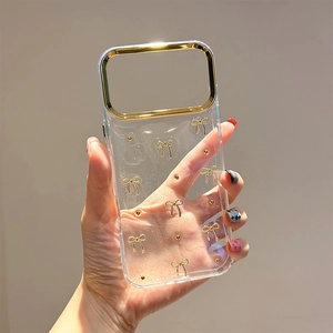 Transparent iPhone case with golden bows and sparkly finish, featuring metal camera frame