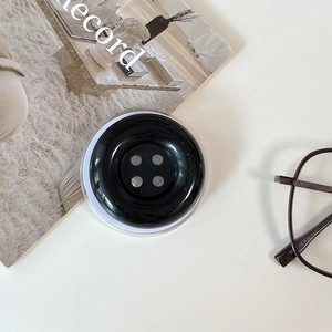 Top view of glossy black button phone socket grip on a minimalist white desk