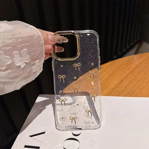 Close-up of clear iPhone case featuring 3D golden bow and sparkling glitter accents