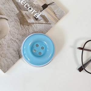 Detail shot of a light blue button shaped phone grip on a minimalist desk setup