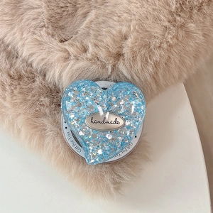 Close-up of heart-shaped blue glitter phone grip with handmade metal tag on gift card