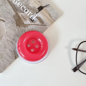 Detail of red candy button phone grip accessory with a glossy finish on white surface