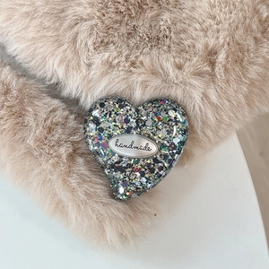 Close-up of a sequin heart-shaped grip with a metallic plate engraved with handmade